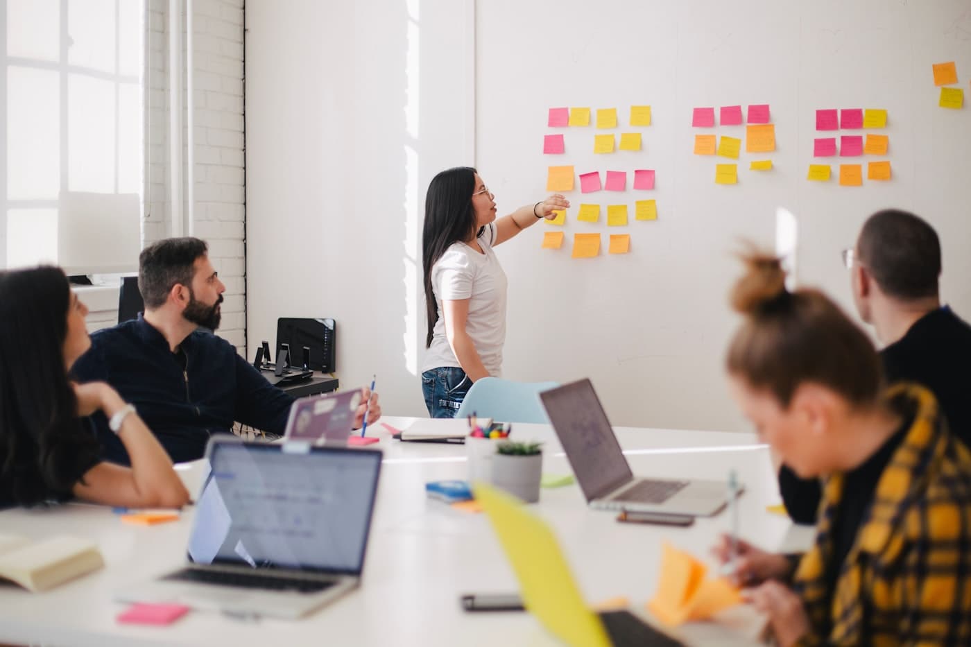 A facilitator leading a small group workshop discussion in front of a board